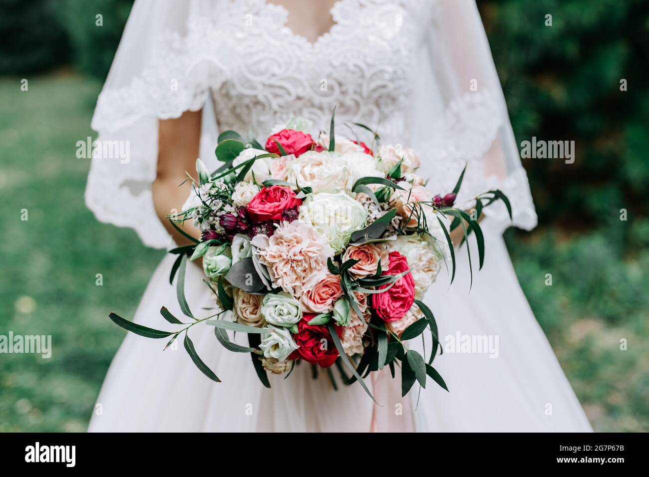 Wunderschöne Braut mit einem tollen Brautstrauß aus roten, weißen, beigen Rosen Stockfoto