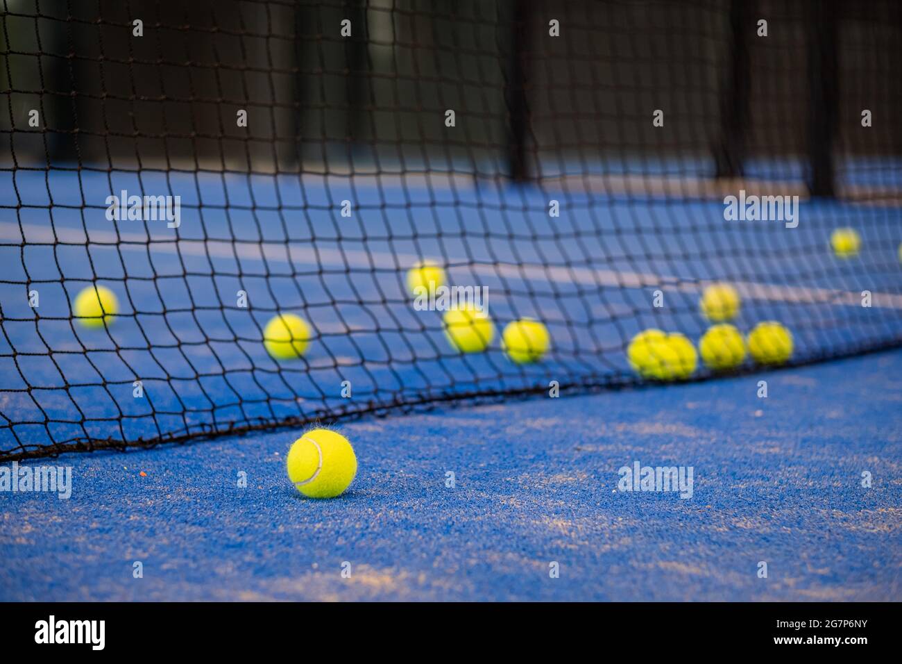 Tennisball auf dem Boden nach einem Spiel - Padel-Kugeln - Gelbe Tennisbälle auf dem Platz auf blauem Rasen Stockfoto