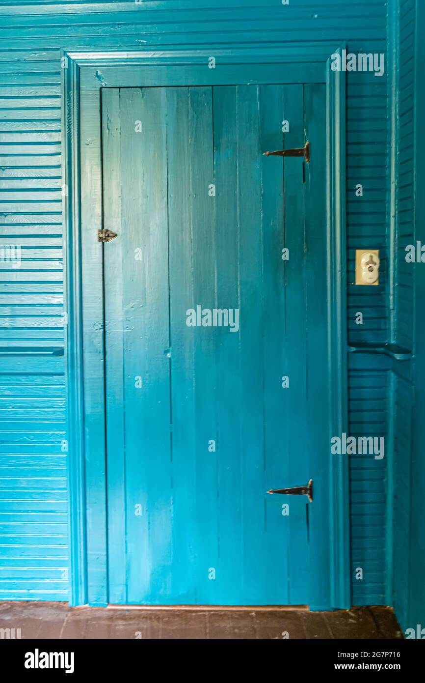 Türkisfarbene innere Schranktür mit den gleichen farbigen Wänden und Zierleisten im alten Haus mit authentischen originalen Wandbehängen. Stockfoto