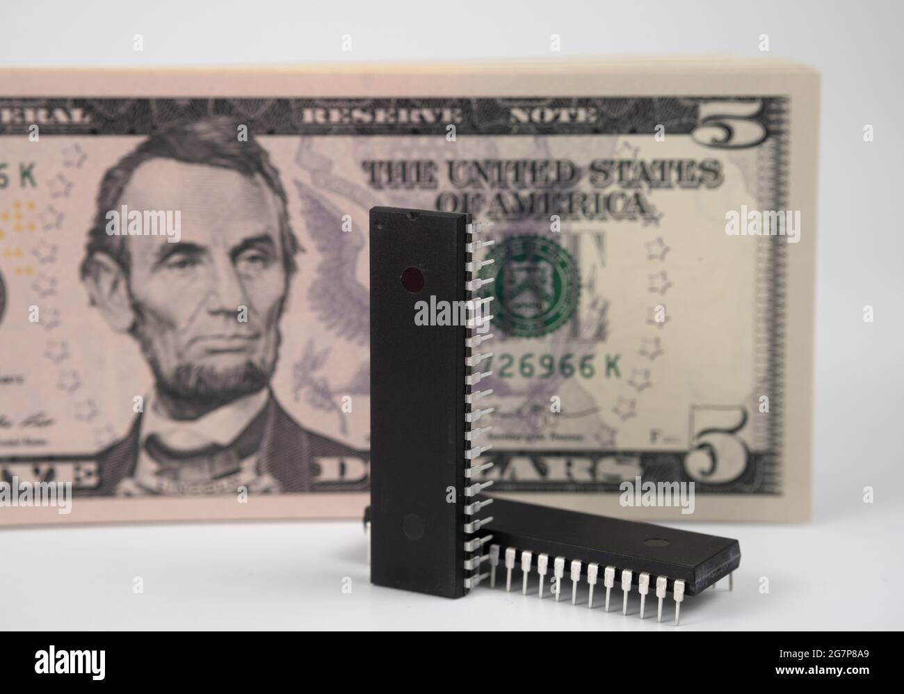 Große Computerchips, die neben 5 US-Dollar-Banknoten platziert werden. Konzept für Investitionen in die Halbleiterindustrie und Golbal-Chipknappheit. Stockfoto