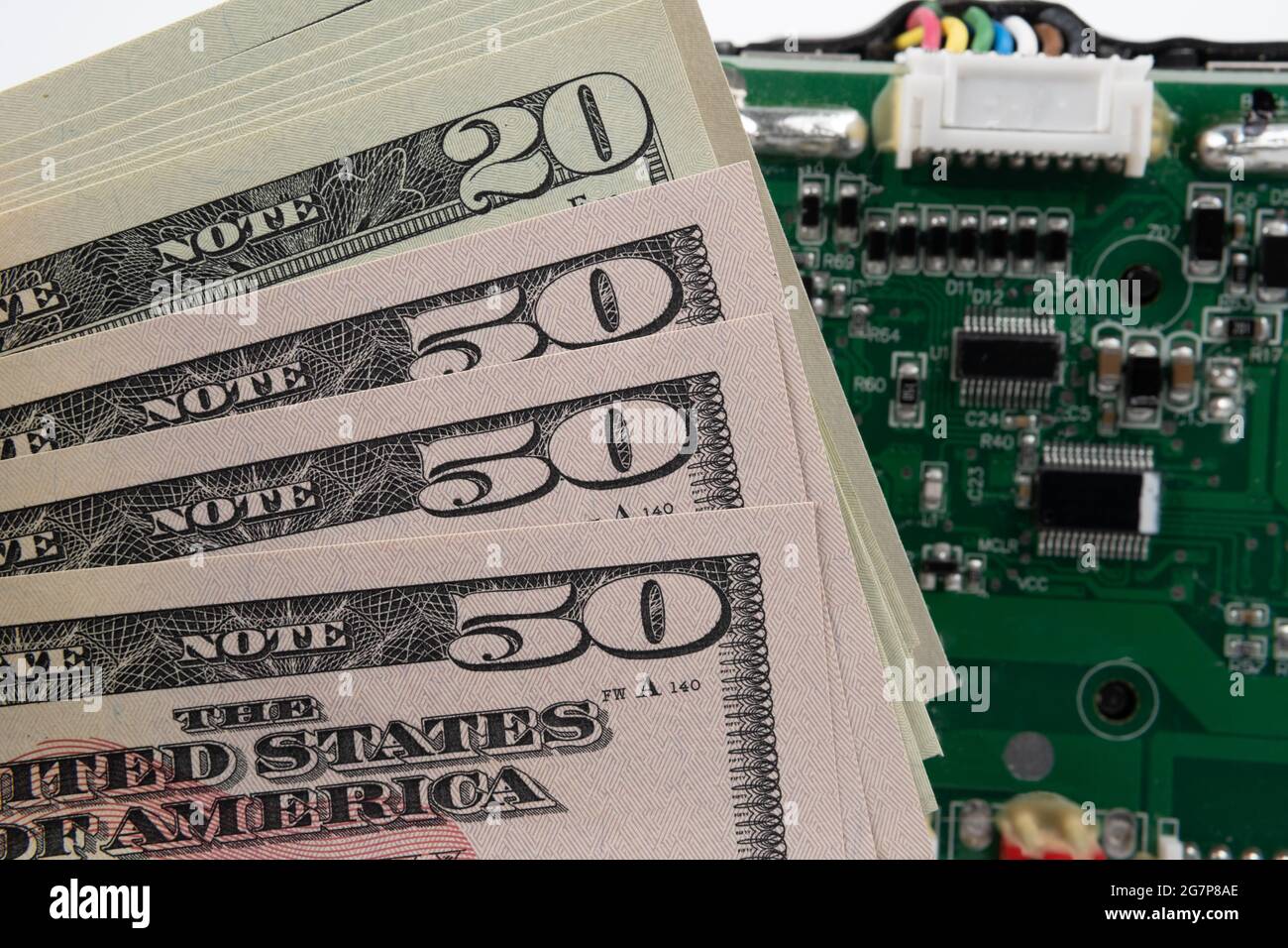 Stapel von US-Dollar-Banknoten und verschwommener Leiterplatte auf dem Hintergrund. Konzept. Stockfoto