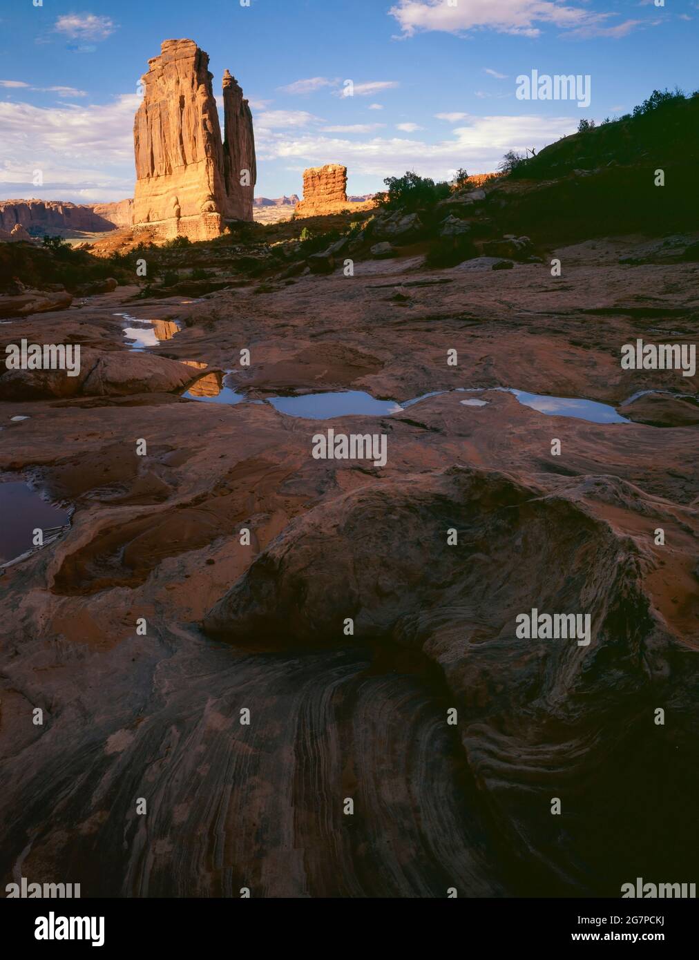 Arches National Park UT / JULY Wassertaschen im glatten Fels des Gerichtsgebäudes Wash spiegeln den blauen Himmel und seinen Namensvetter butte wider. Stockfoto