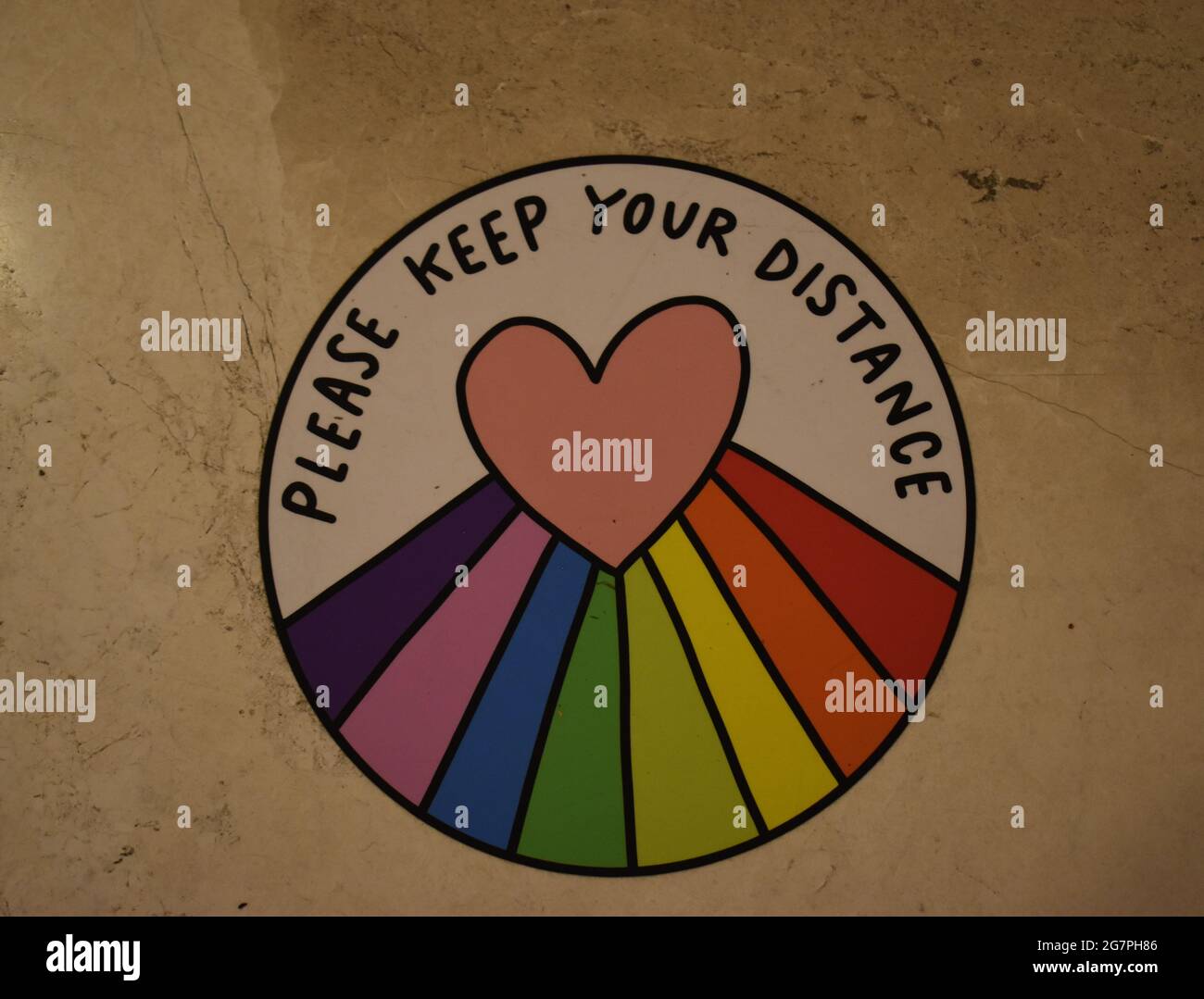 Schild: 'Bitte halte Abstand', mit Regenbogen und Herz. Stockfoto
