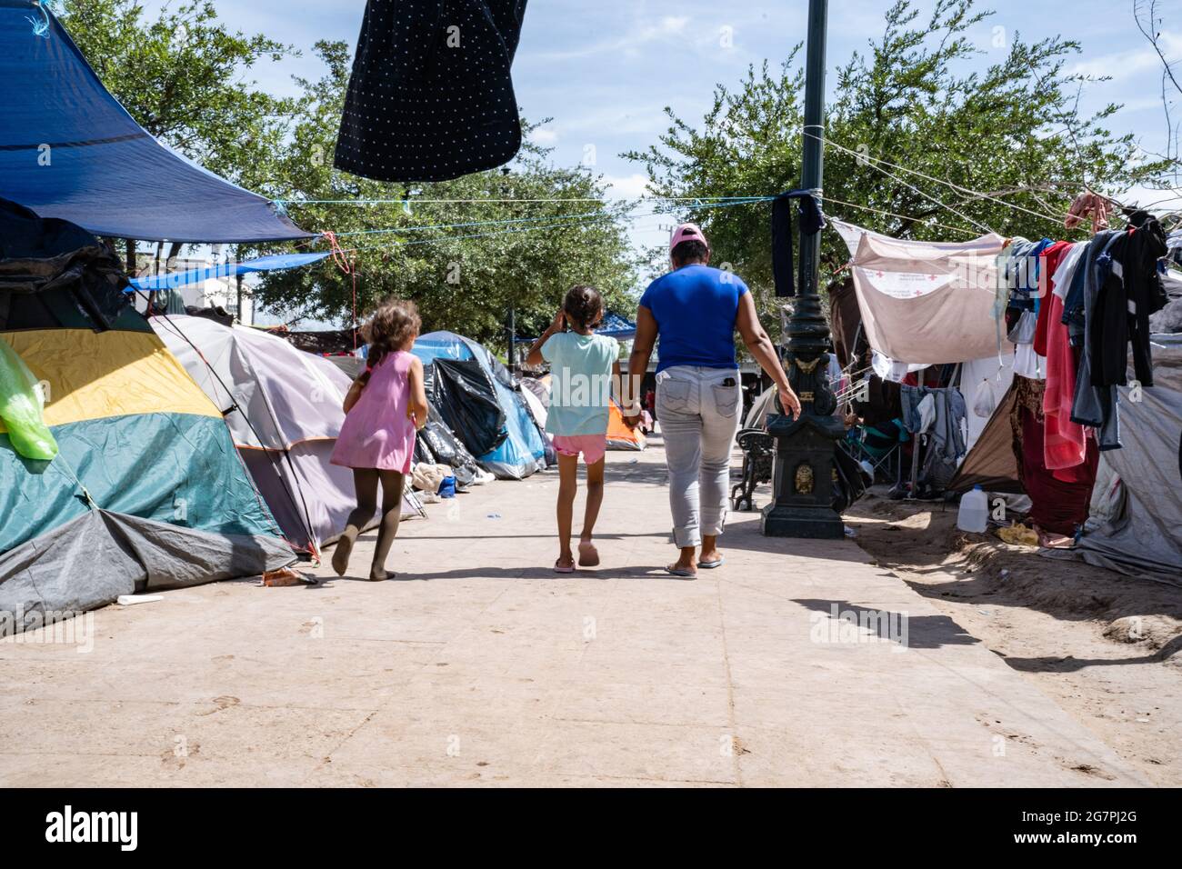 Reynosa, Mexiko. 15. Juli 2021. Eine Mutter und ein Kind gehen einen der arteriellen Pfade des Zeltlagers für Migranten entlang, das sich auf dem Hauptplatz neben der Internationalen Brücke gebildet hat. Quelle: Lexie Harrison-Cripps/Alamy Live News Stockfoto