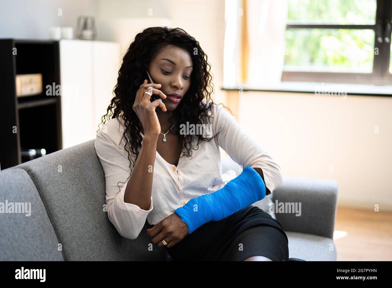 Verletzte Frau, Die Nach Einem Unfall Zu Hause Telefonische Gespräche Geführt Hat Stockfoto