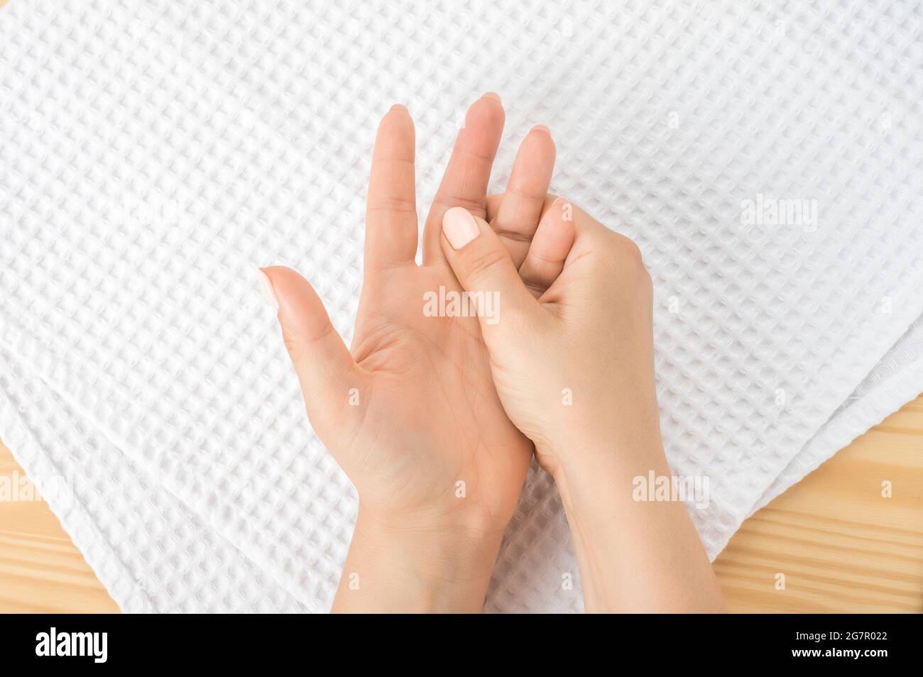 kaukasische Frau mit der Hand auf ihrem ungesunden Finger und ihrer Handfläche. Selbstmassage, Office-Syndrom und muskelschmerzen. Eine weibliche Hand massiert die andere Hand Stockfoto