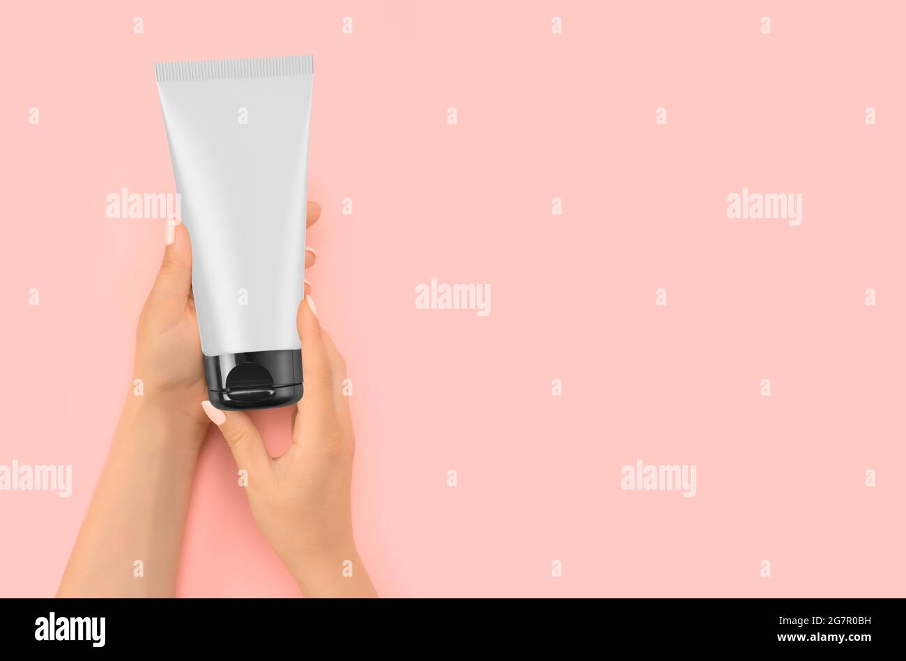 Hand hält Mockup Kosmetische Kunststoffröhre isoliert auf rosa Hintergrund. Creme Tube in der Hand Creme auf Soft Silky gesunde Haut Pflegekonzept . Schöner Wo Stockfoto