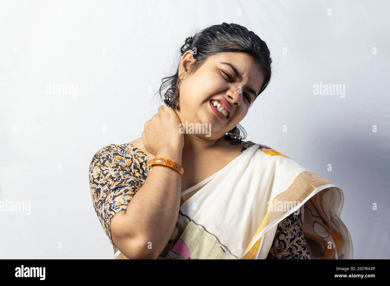 Isoliert auf weißem Hintergrund eine indische Frau in Saree hält Hals Gesicht Schmerzen Stockfoto
