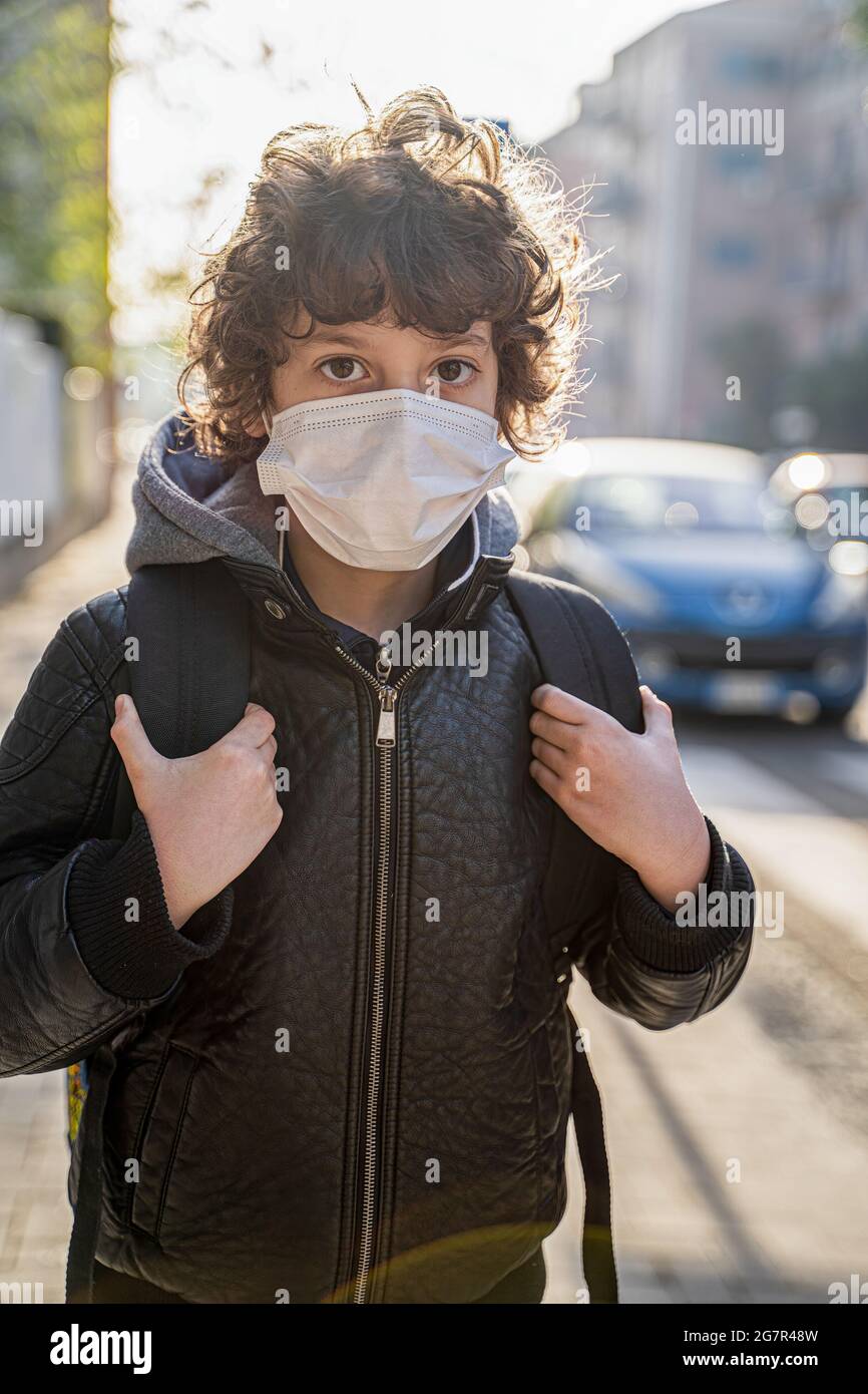 Schuljunge mit Rucksack zurück in die Schule mit Gesichtsmaske. Neun Jahre altes Kind, das im Coronavirus auf der Straße läuft, ist normal. Stockfoto