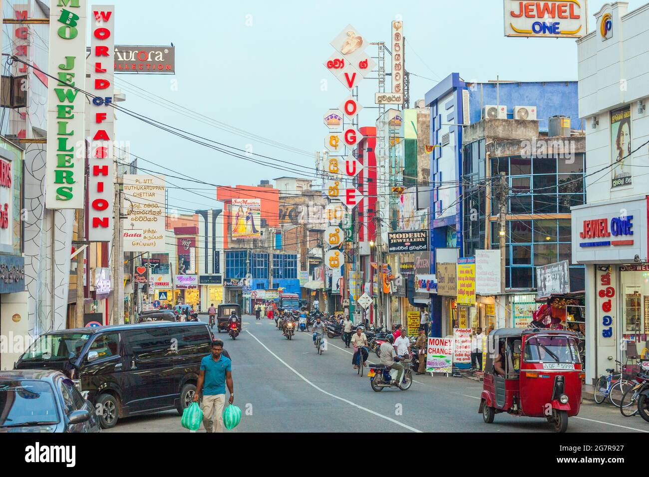 Blick auf geschäftige Hauptstraße mit Fahrzeugen, Ladenfronten und bunten Plakatwänden, Negombo, Sri lanka Stockfoto