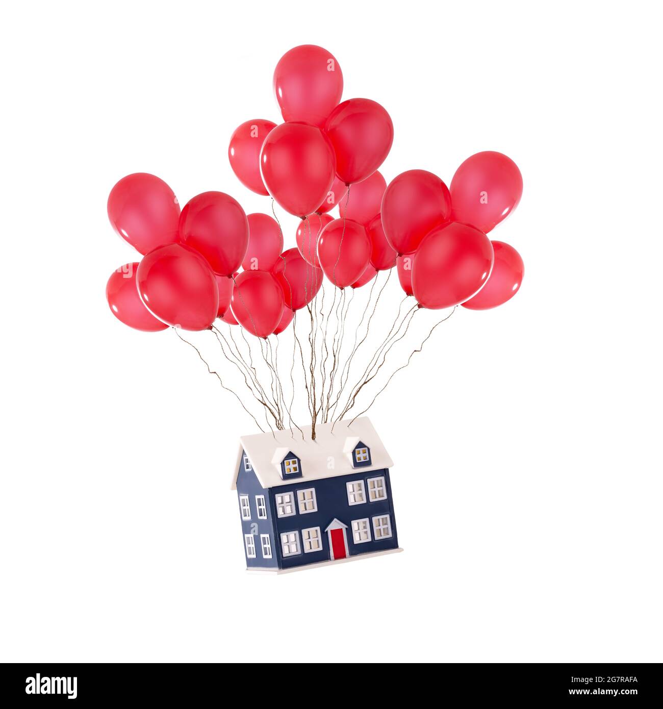 Spielzeughaus schwebt mit roten Ballons isoliert auf weißem Hintergrund. Umzug und neues Hauskonzept für Immobilienmakler Stockfoto