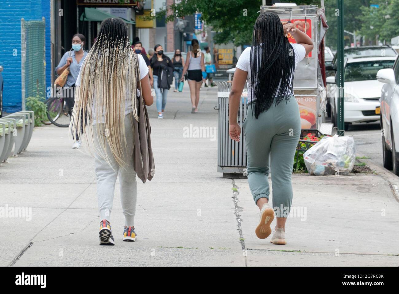 Zwei Frauen mit sehr langen Haarverlängerung gehen auf der Steinway Street in Astoria, Queens, New York, Stockfoto
