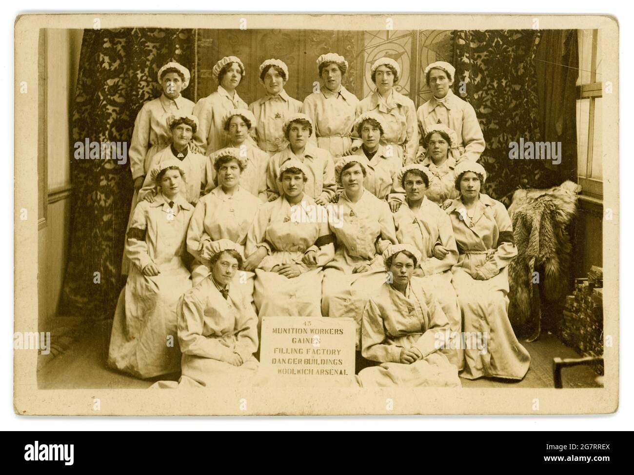 Die ursprüngliche Postkarte aus der Zeit von WW1 lautet: „Munitionsarbeiter Gaines“, die Gebäude der Fabrik füllen Woolwich Arsenal, die Frauen tragen „Kriegsdienstabzeichen“, veröffentlicht 1917, Woolwich, London, Großbritannien Stockfoto
