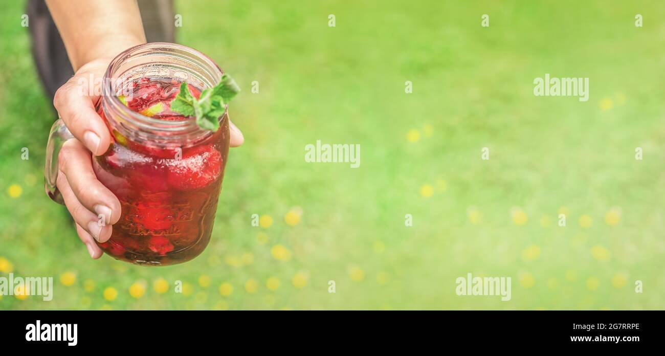 Eine Person, die einen erfrischenden Sommerdrink anbietet. Breitbild mit Textbereich Stockfoto