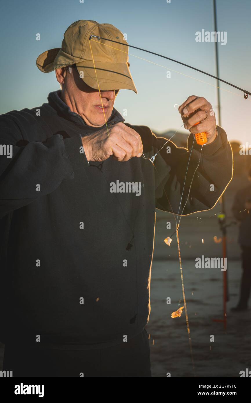 Vertikale Aufnahme eines erfahrenen argentinischen Fischers, der Köder an den Haken seines Angelpols befestigt Stockfoto
