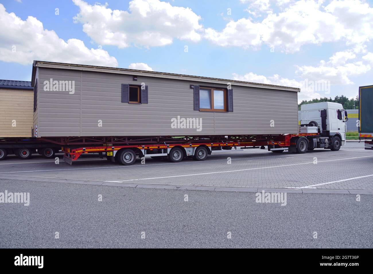 Ein sehr langes und breites Fahrzeug. Übergroße Ladung oder außergewöhnlicher Konvoi. Ein LKW mit einem speziellen Sattelauflieger für den Transport von überdimensionaler Ladung - transp Stockfoto