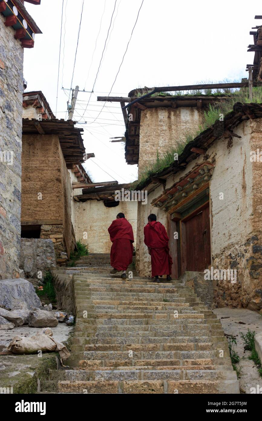 Zwei buddhistische Mönche in traditionellen Kostümen, die die Treppe zum Tempel in Shangri-La, China, hinaufgehen Stockfoto