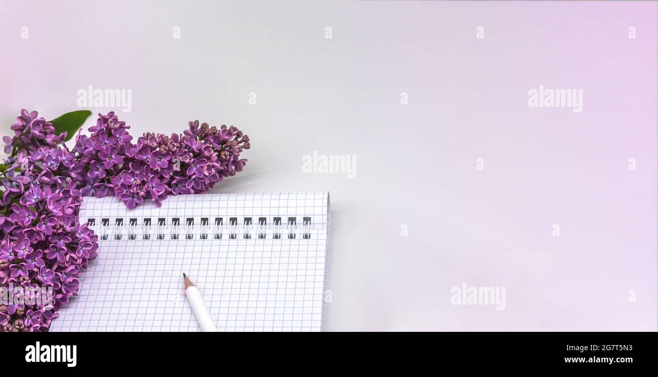 Notizblock mit Stift und Blumen. Spiralnotizbuch und Stift. Notebook-Flieder auf hellem Hintergrund. Stockfoto