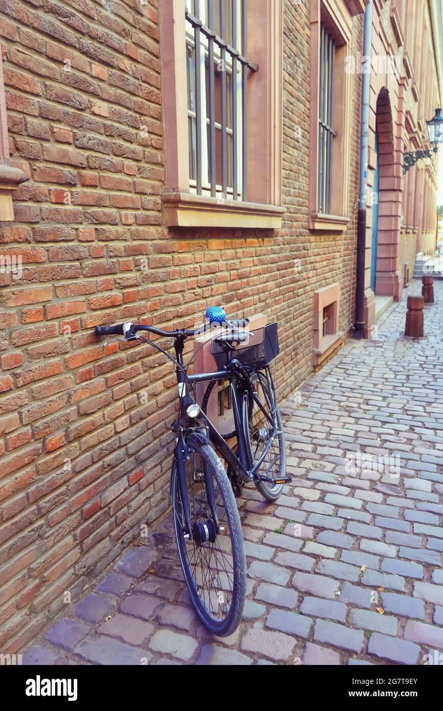 Blick auf eine Seitenstraße in der historischen Altstadt von Düsseldorf, Deutschland, mit Vintage-Fahrrad, Backsteingebäude und Pflastersteinpflaster. Stockfoto