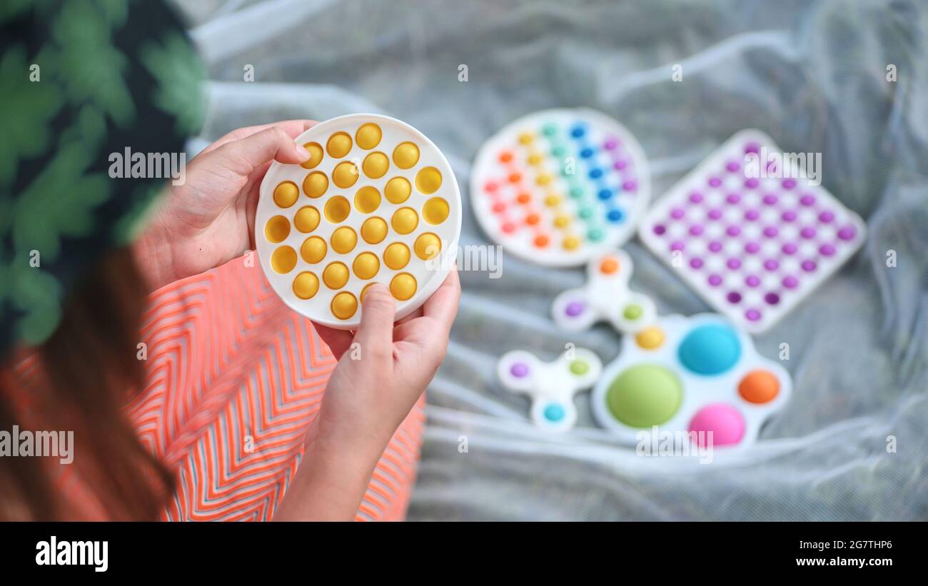 Teenager Mädchen spielt mit Anti-Stress-Spielzeug popit und einfache Grübchen im Park an einem Sommertag. Stockfoto