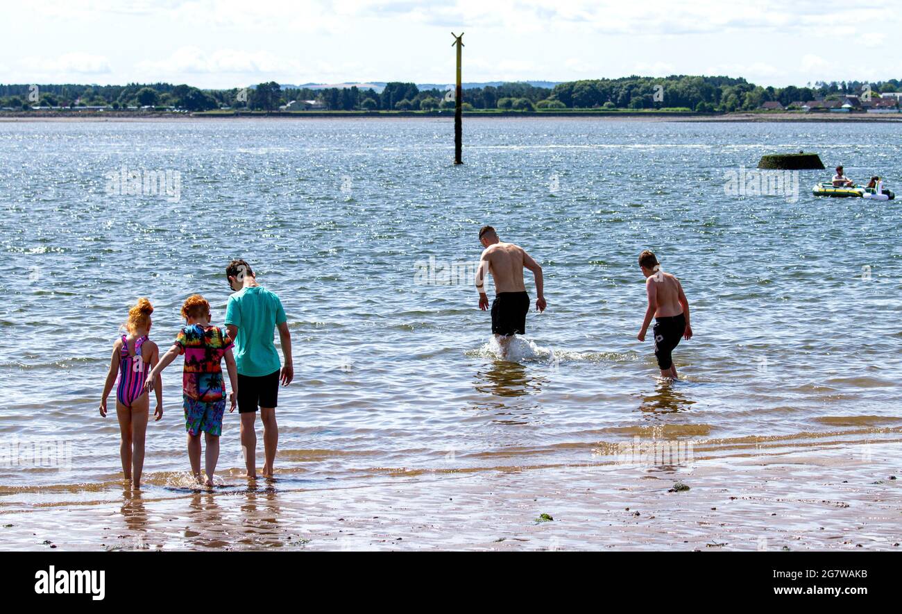 Dundee, Tayside, Schottland, Großbritannien. Juli 2021. UK Wetter: Heisses, sonniges Wetter, das durch Nordostschottland weht mit einer Höchsttemperatur von 29 Grad Strandbesucher können den Tag am Broughty Ferry Beach in Dundee ausklingen lassen und die warme, herrliche Sommersonne genießen. Junge Leute spielen im Wasser, bevor sie im Fluss Tay schwimmen gehen. Kredit: Dundee Photographics/Alamy Live Nachrichten Stockfoto