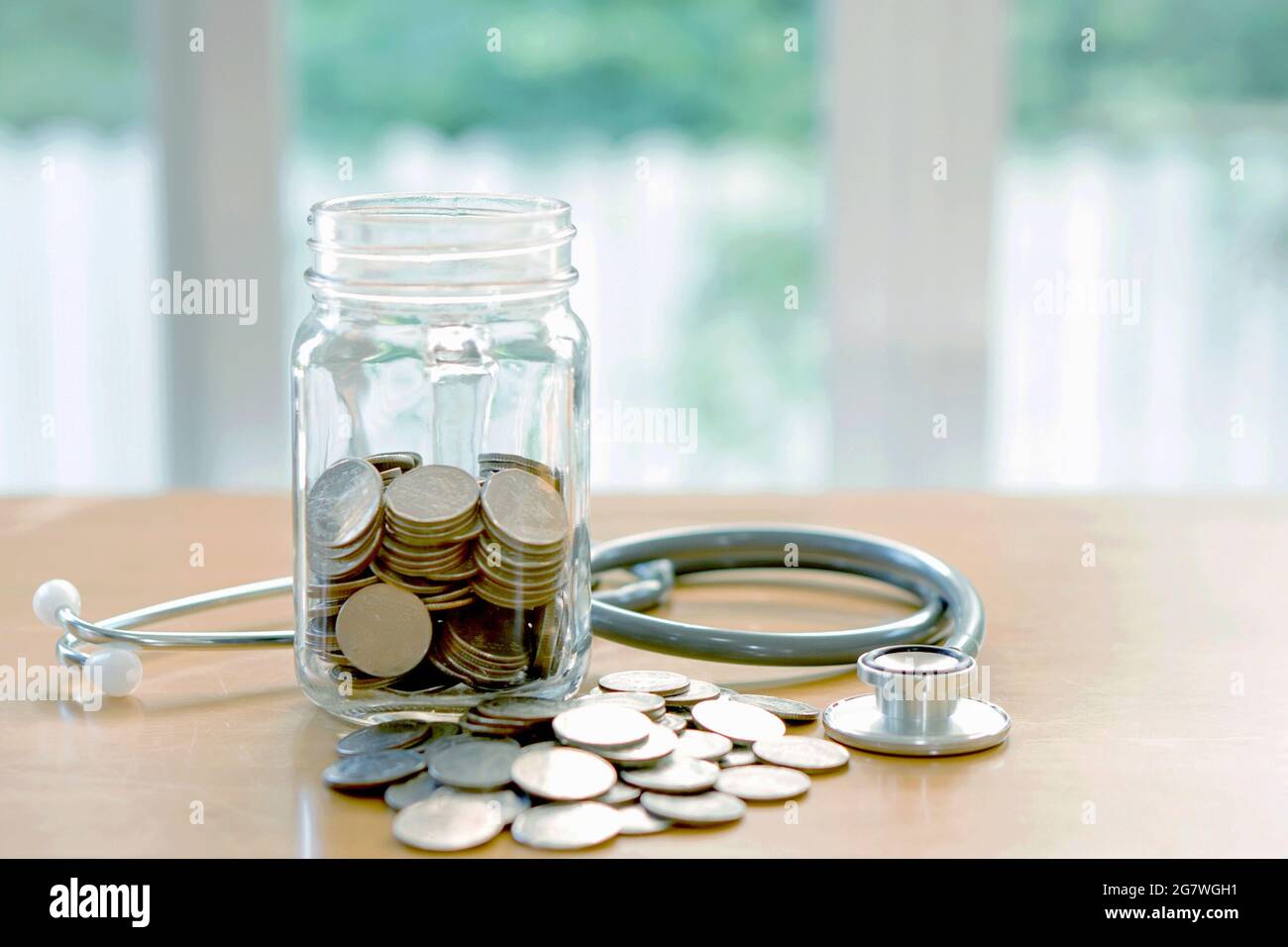 Bildungsbudget-Konzept. stethoskope Geldeinsparungen im Glas Stockfoto
