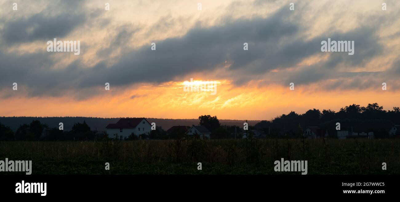 Morgensonne über dem Dorf, die aufwachende orangefarbene Sonne außerhalb der Stadt. Stockfoto