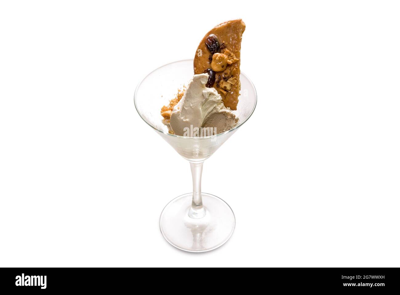 Eiscreme mit karamellisiertem Keks und Haselnüssen in martiniglas, isoliert auf weißem Kopierraum Stockfoto