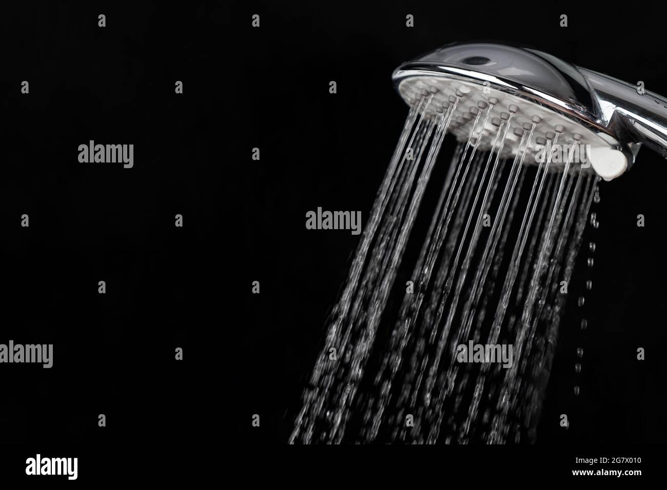 Streuen von Spritzwasser durch einen Duschkopf auf dunklem Grund. Stockfoto