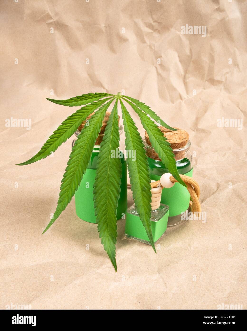 Flaschen mit Extraktöl und medizinischem Cannabis auf Papierhintergrund. Stockfoto