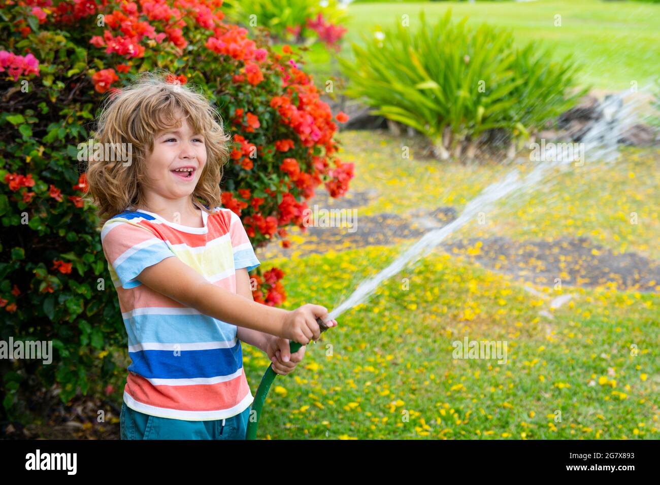 Süßer kleiner Junge, der am Sommertag Blumen im Garten wässert. Kind mit  Gartenschlauch. Lustige Kinder Bewässerung Pflanzen im Garten  Stockfotografie - Alamy