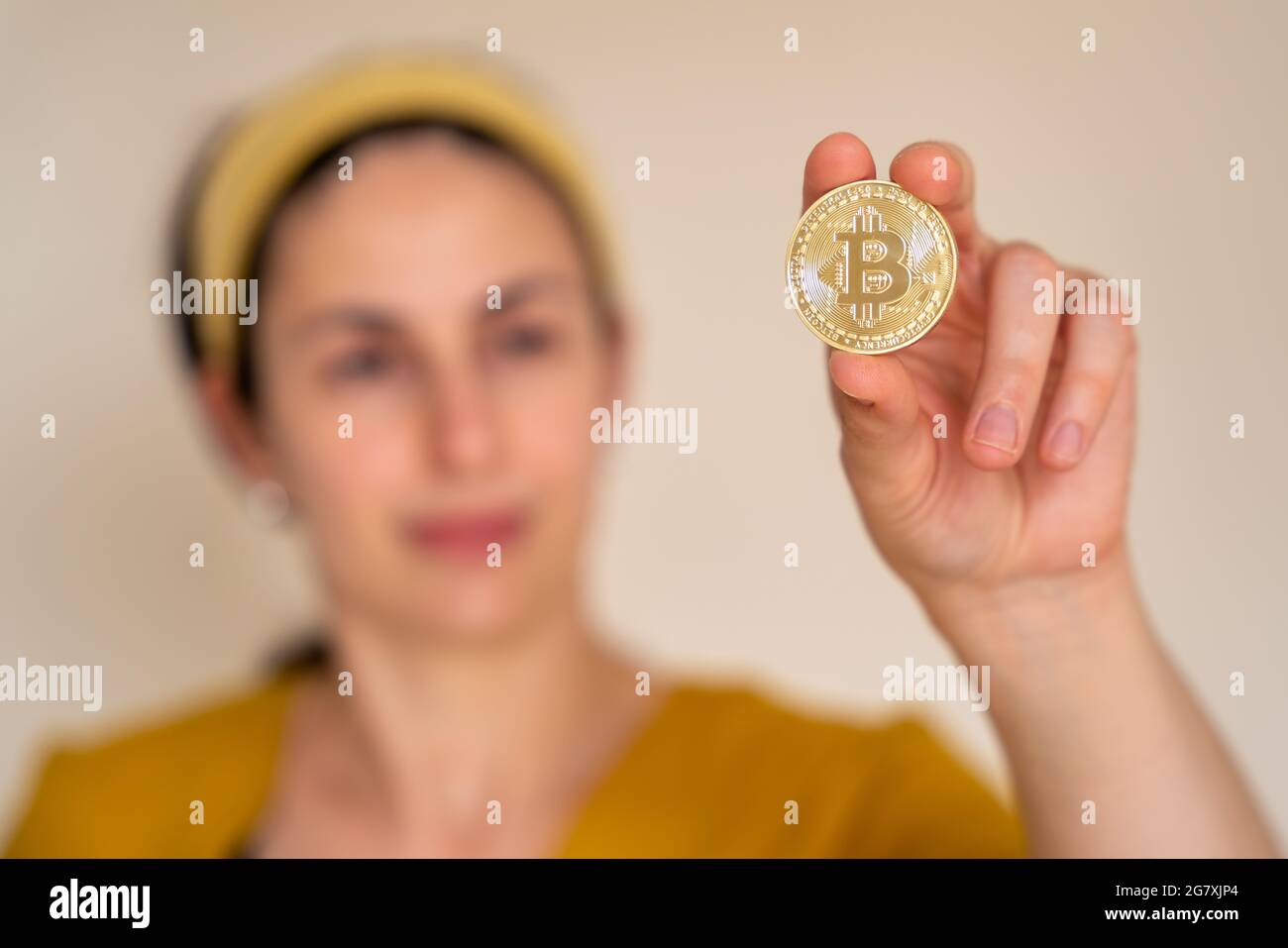 Nahaufnahme einer Frau, die Bitcoin-Kryptowährungsmünze in der Hand hält Stockfoto