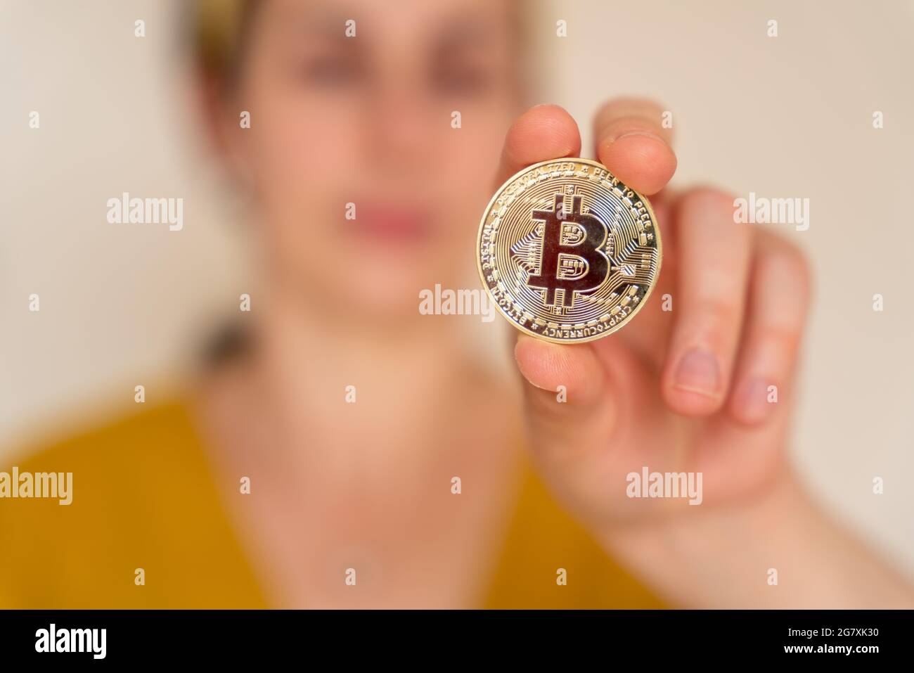 Nahaufnahme einer Frau, die Bitcoin-Kryptowährungsmünze in der Hand hält Stockfoto