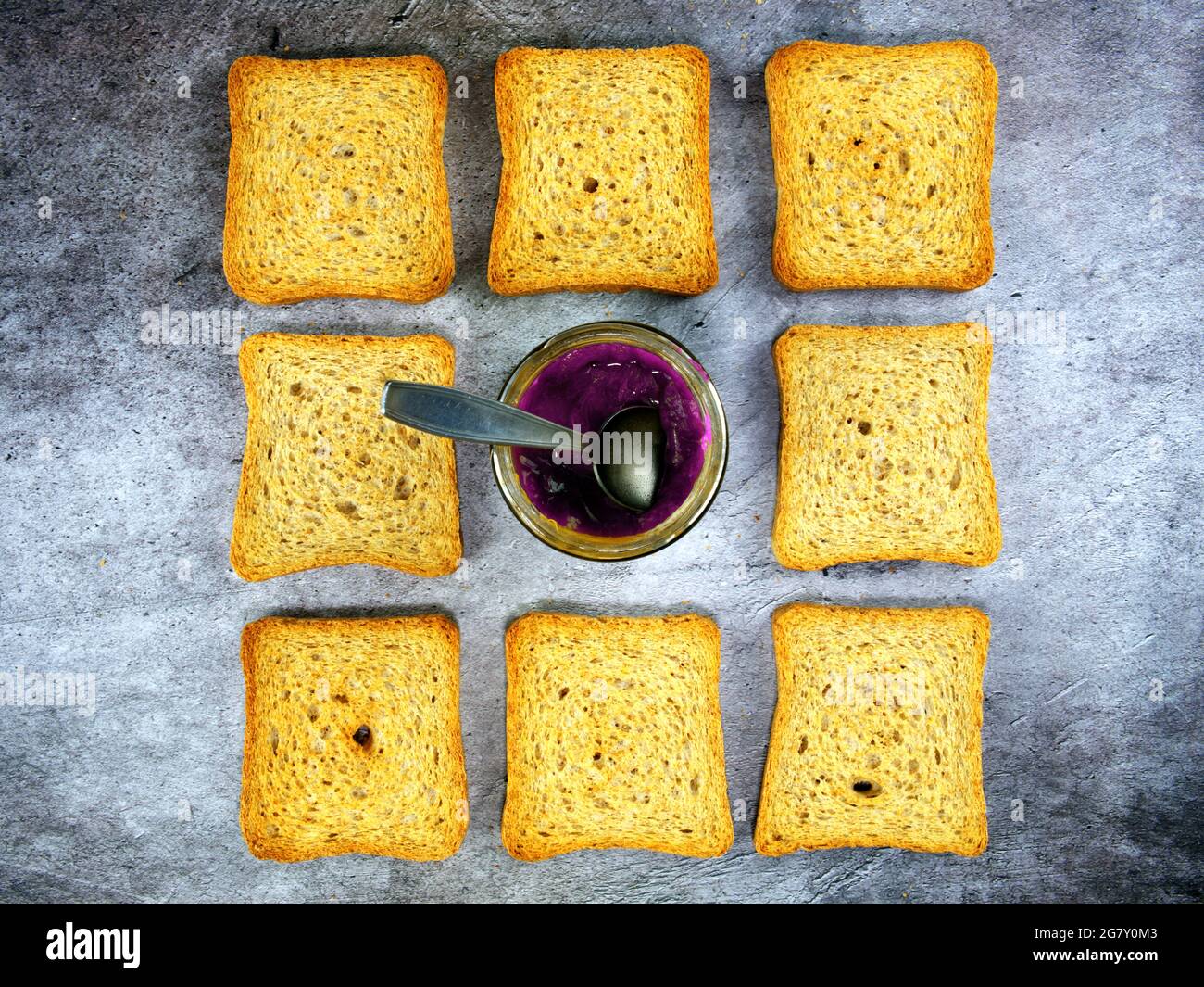 Flaches Lay Teelöffel in ein Glas Weingelee mit Zwieback getaucht Stockfoto