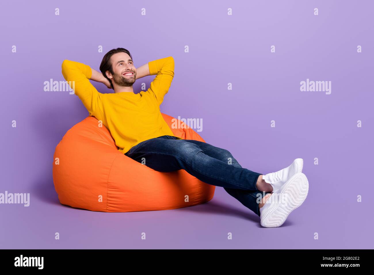 In voller Länge Körpergröße Foto Mann liegt in Sitzsack chillig verträumt suchen Kopyspace isoliert pastelllila Farbe Hintergrund Stockfoto
