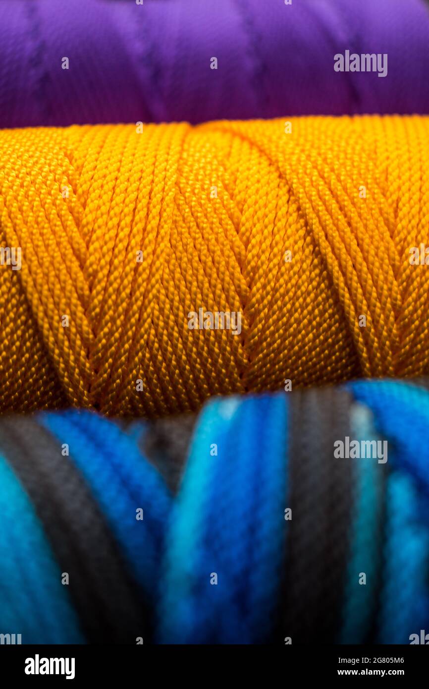 Nahaufnahme von verschiedenen bunten Fadenrollen auf einer bunt gestreiften Matte Stockfoto