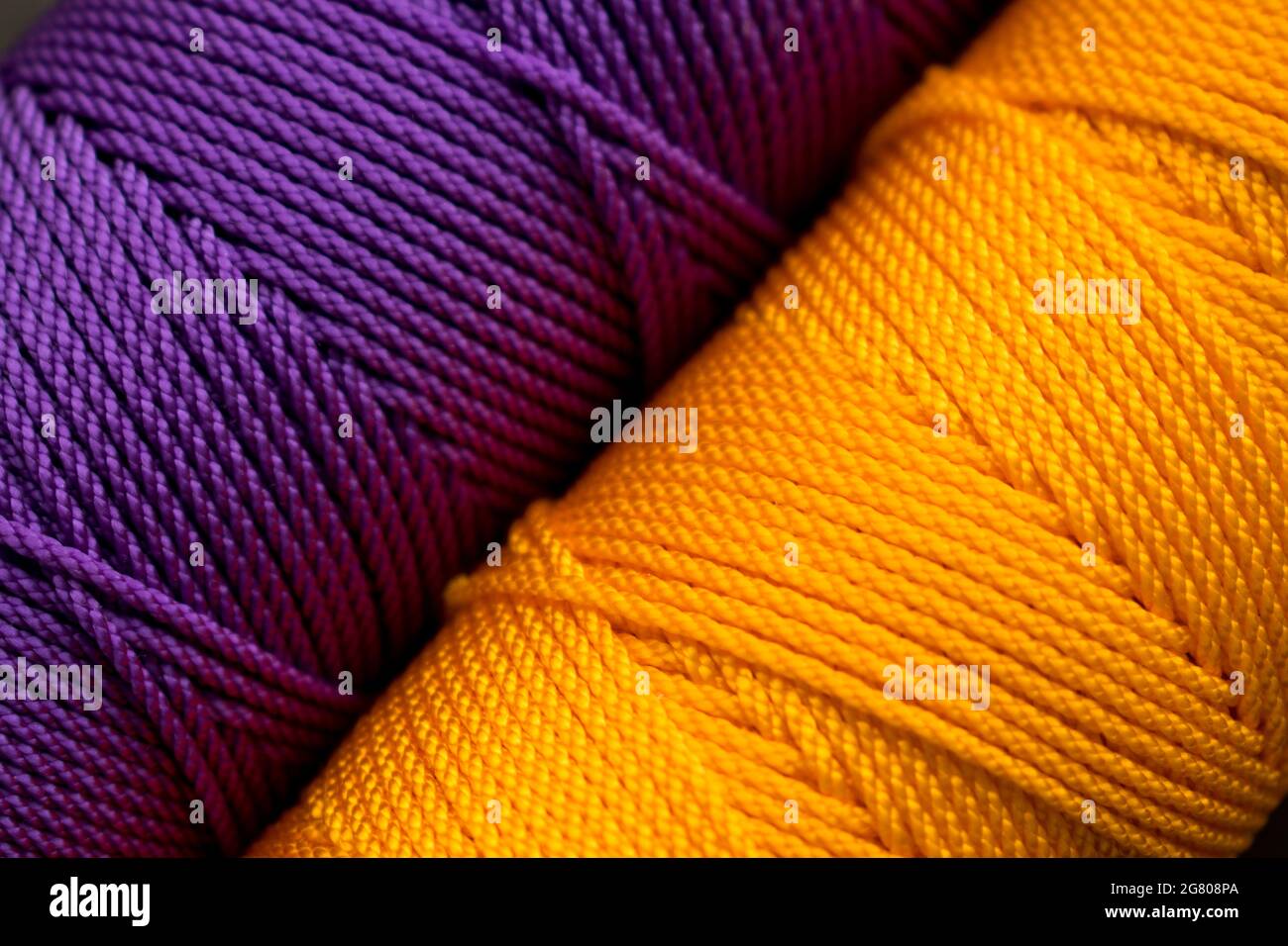 Nahaufnahme von verschiedenen bunten Fadenrollen auf einer bunt gestreiften Matte Stockfoto