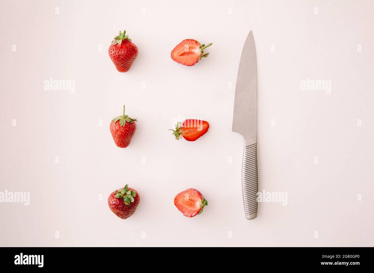 Frische rote Erdbeerfrucht und Messer auf weißem Hintergrund. Draufsicht, flach liegend. Stockfoto