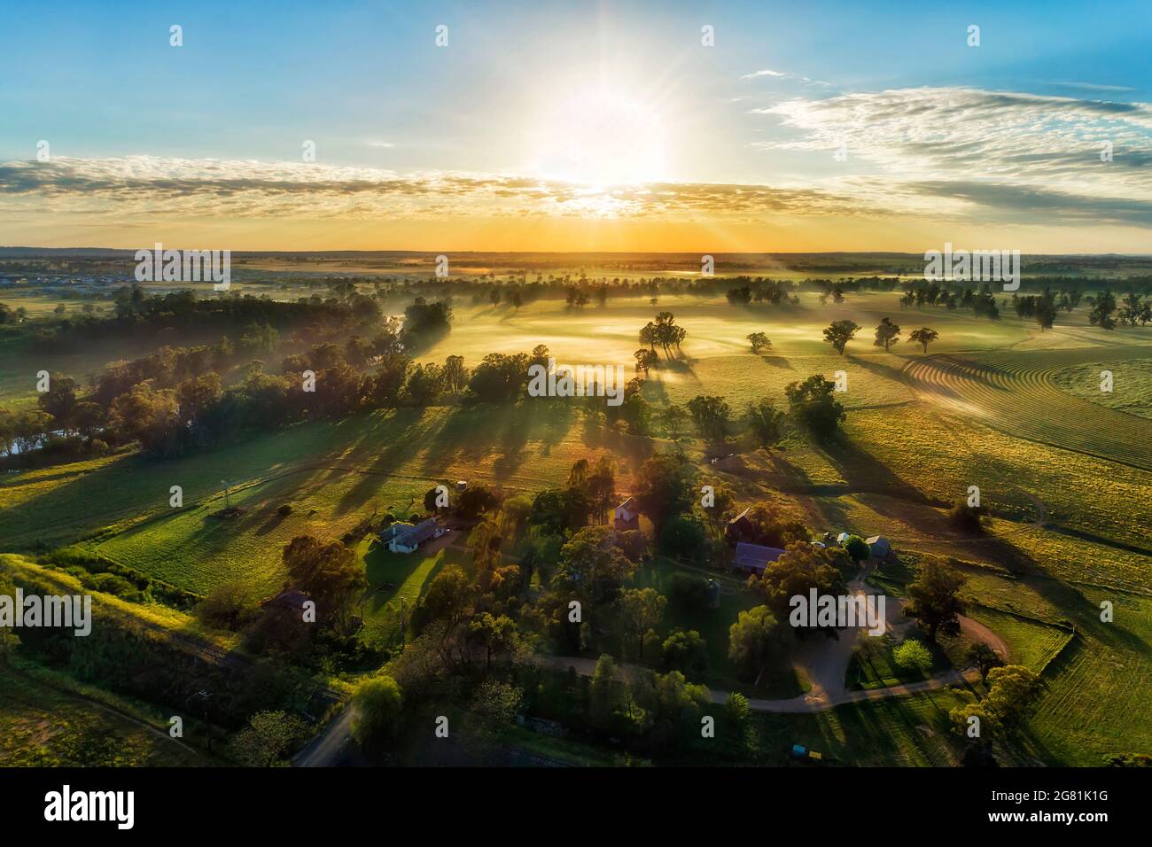 Abgeschiedenes Gehöft auf landwirtschaftlichen Kulturfeldern in der Nähe des Macquarie River in der australischen Stadt Dubbo - Sonnenaufgangsansicht aus der Luft. Stockfoto