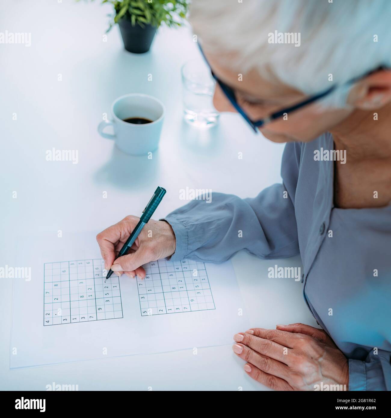 Ältere Frau löst Sudoku-Rätsel Stockfoto