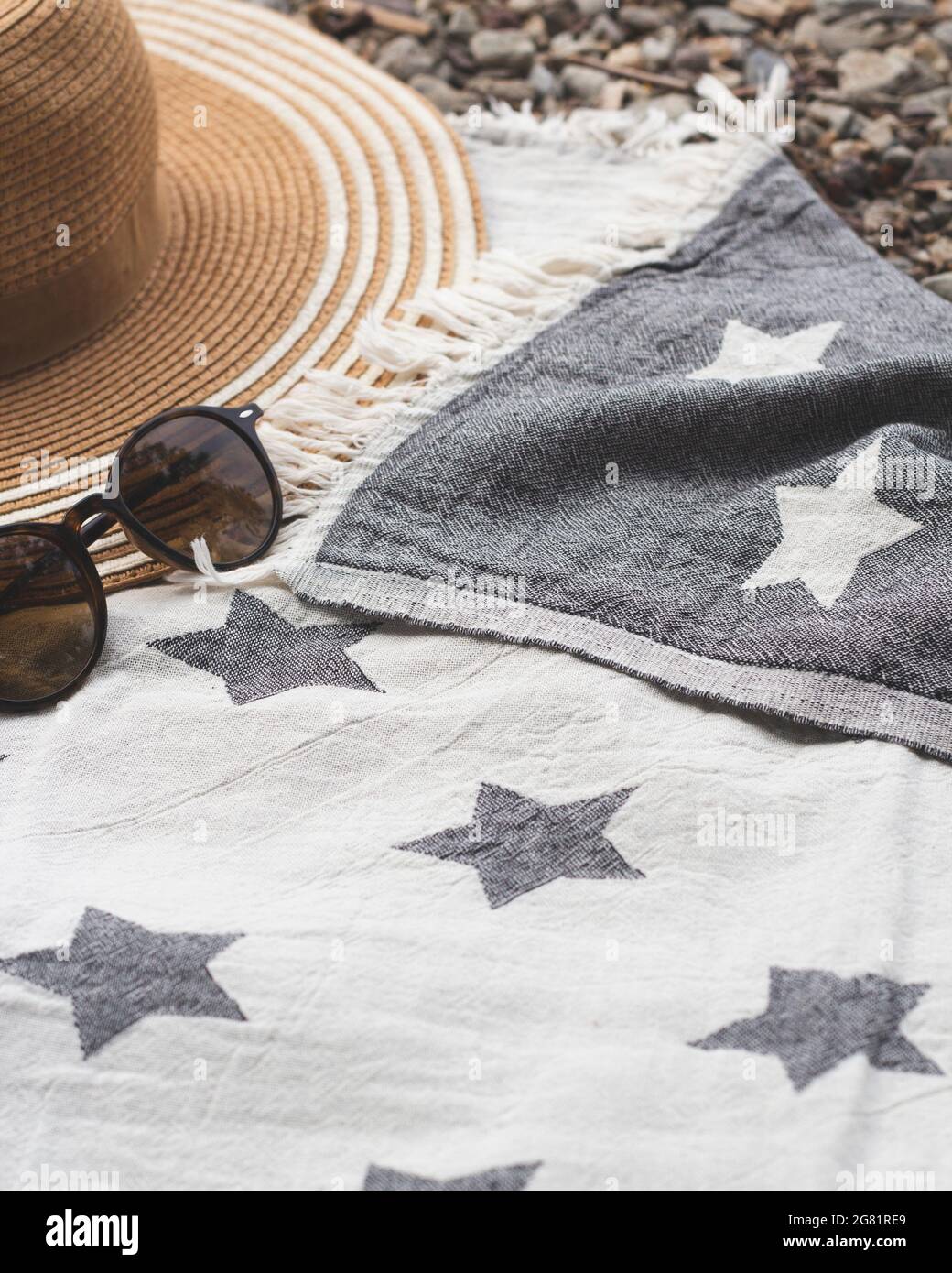 Sommerkonzept mit Strohhut und Sonnenbrille auf Strandtuch. Nahaufnahme. Stockfoto