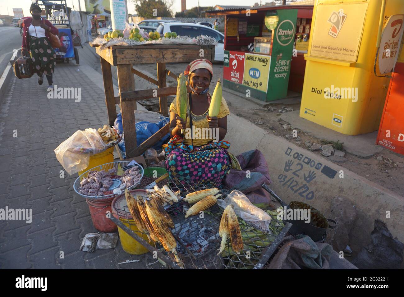 Lusaka, Sambia. Juli 2021. Idah Sakala, ein Wiederverkäufer von frischem Mais, posiert am 1. Juli 2021 in Lusaka, Sambia, mit frischen Maiskolben. Heute kann man an jedem Tag des Jahres eine frische Maiskolben genießen, weil die landwirtschaftlichen Technologien wie Bewässerungssysteme und die Einführung von früh reifenden Saatgutsorten Fortschritte machen. Kredit: Lillian Banda/Xinhua/Alamy Live Nachrichten Stockfoto