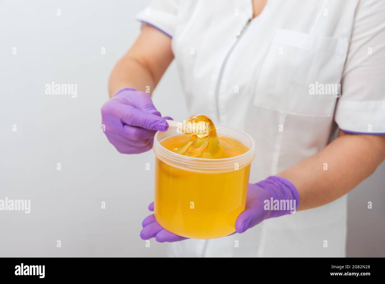 Natürliche Honigzucker-Paste shugaring Nahaufnahme. Frauen Kosmetikerin hält Glas Wachs aus Paste für Zucker Enthaarung shugaring, weißen Hintergrund Stockfoto