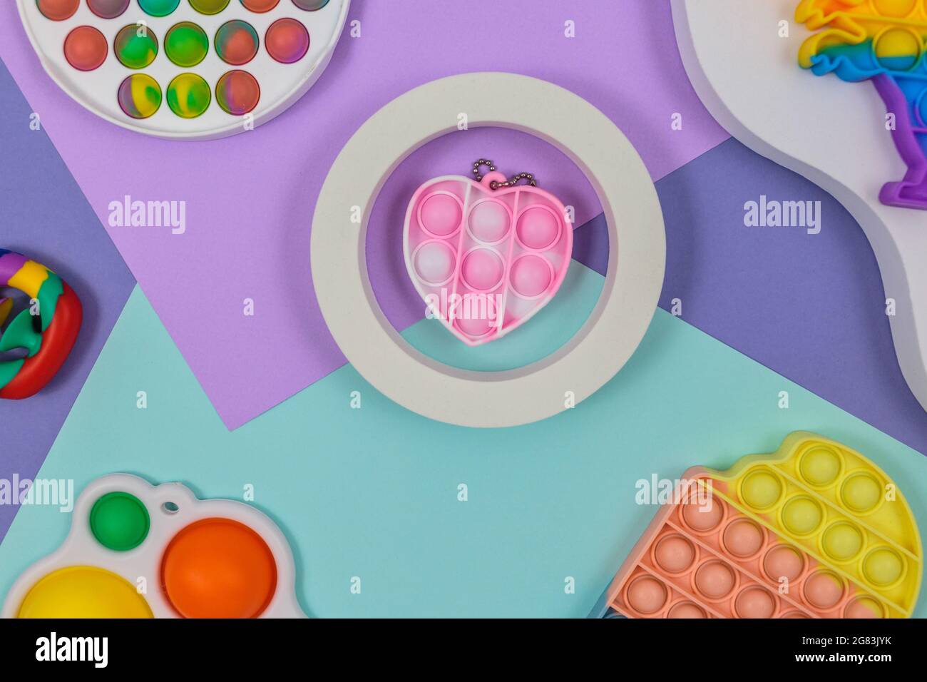 Beliebte Silikon-Anti-Stress-Pop-it-Spielzeug für ein Kind auf dem gelb-violetten grün-blauen Hintergrund. Trendiges Reliever Stress Sensory Fidget Spielzeug. Stockfoto