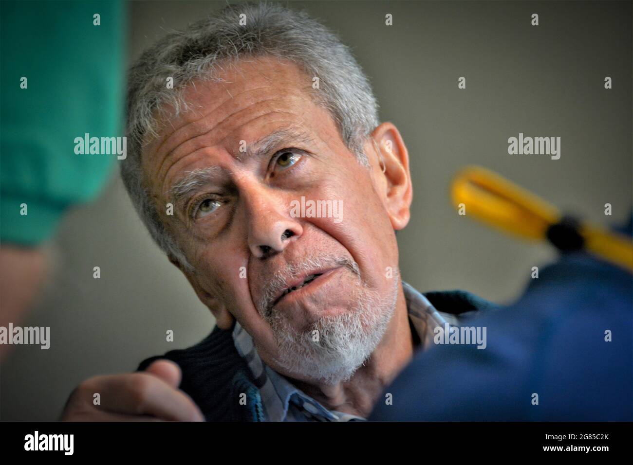 Älterer Mann mit weißen Haaren und Bart fragt und stellt eine Frage zu einem neuen Thema in medizinischen Verfahren, das er sich gerade von einem Chirurgen unterziehen wird Stockfoto