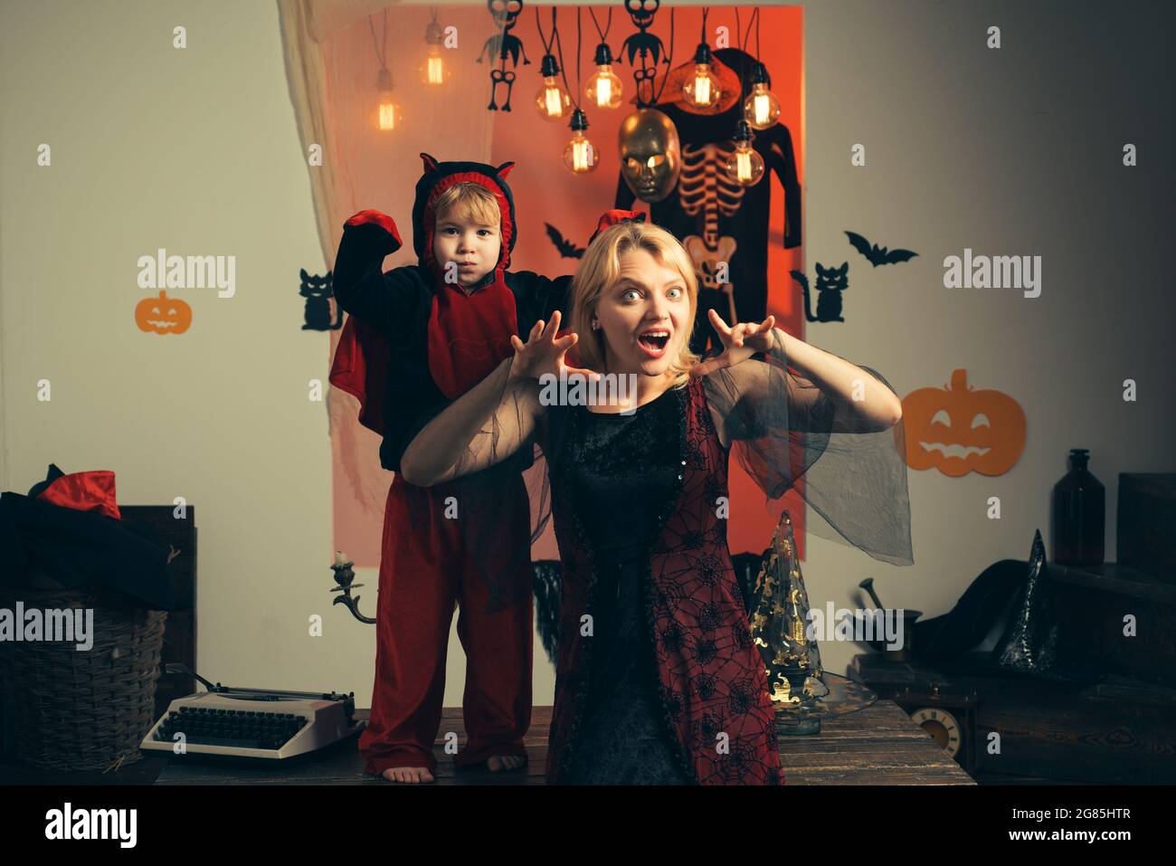 Mutter trägt als Hexe, Sohn trägt als Teufel. Junge in Teufel Kostüm.  Schöne junge Frau mit einem Kind mit Kürbissen Herbst. Lächelnde Mutter und  Sohn Stockfotografie - Alamy