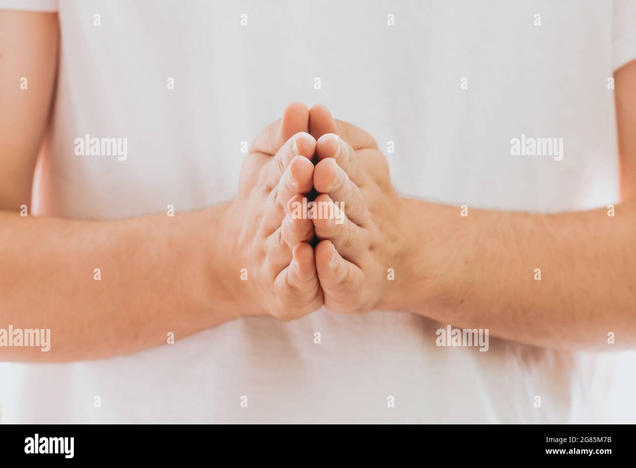 Ein Paar Hände in Gebetsstellung vor weißem Hintergrund - Kraft der Hoffnung oder Liebe und Hingabe Stockfoto