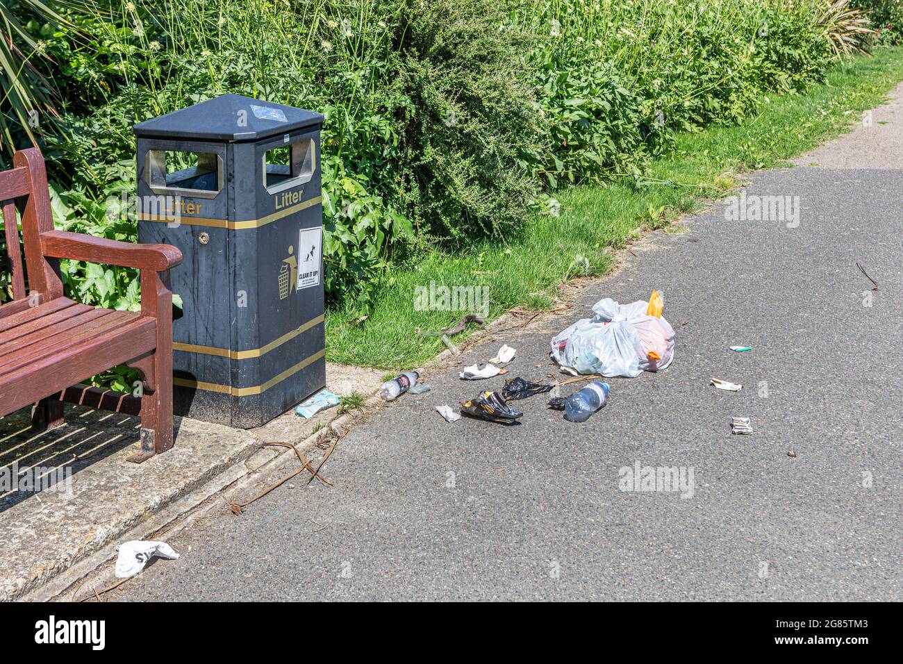 Anti-Sozialabfall auf einem Fußweg in der Nähe eines Abfallbehälters gelassen Stockfoto