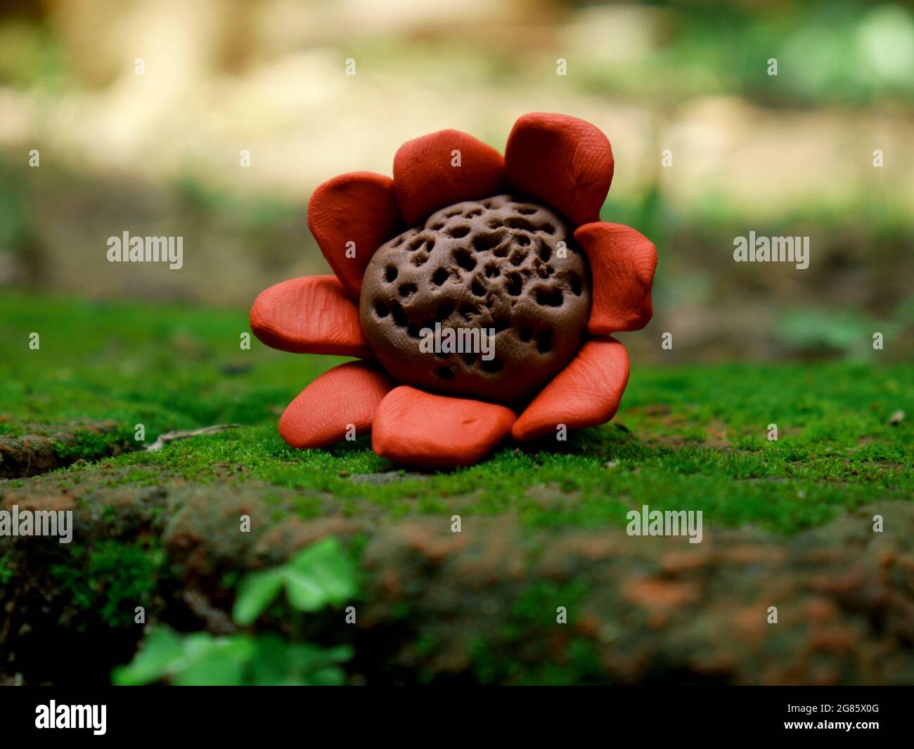 Handgefertigte Ton Kunst Sonnenblume liegt auf natürlichem grünen Gras Oberfläche bei Unschärfe weiten Hintergrund. Stockfoto