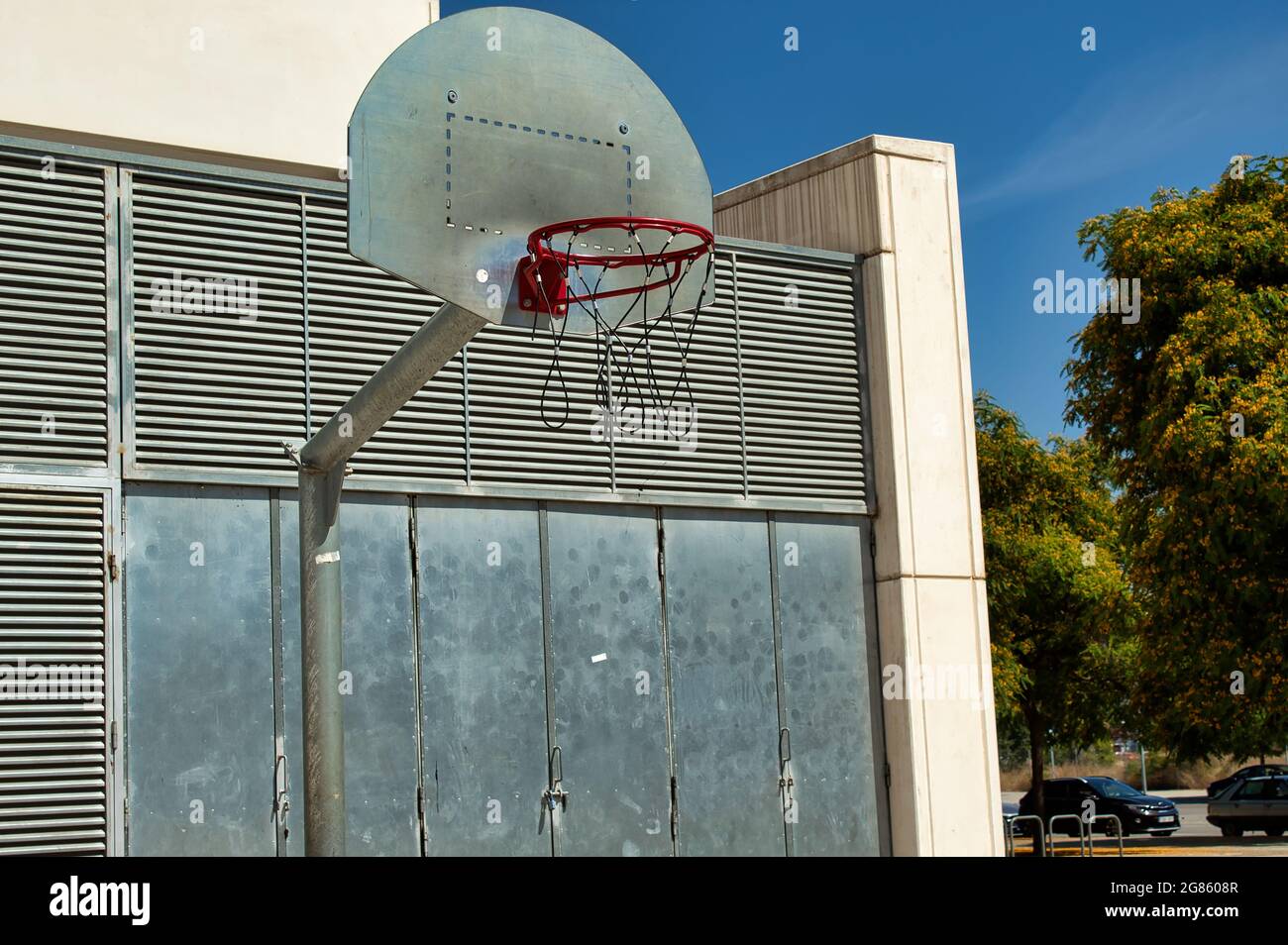 Basketballkorb aus Metall auf der Straße, umgeben von Gebäuden Stockfoto